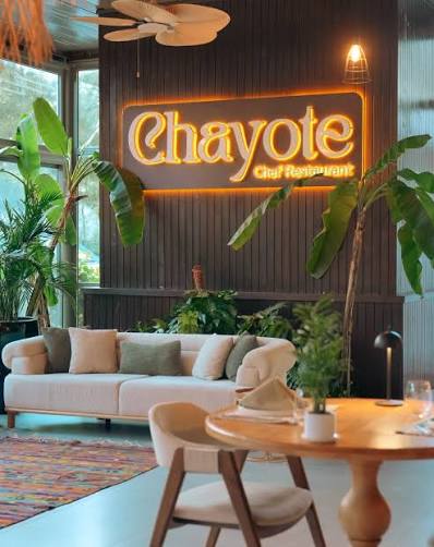 Chayote Chef Restaurant'ın neon tabelalı, yeşilliklerle dolu iç mekânı